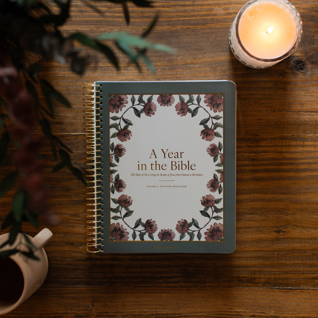 A Year in the Bible Vol 4 cover next to a lit candle on a wooden table